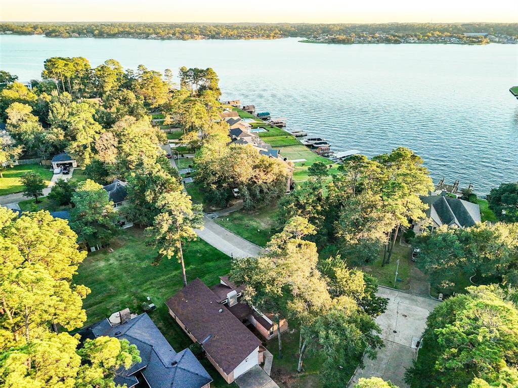 This photo showcases a serene lakeside neighborhood with lush greenery and waterfront properties. The homes are nestled among mature trees, offering privacy and scenic views of the expansive lake, ideal for tranquil living.
