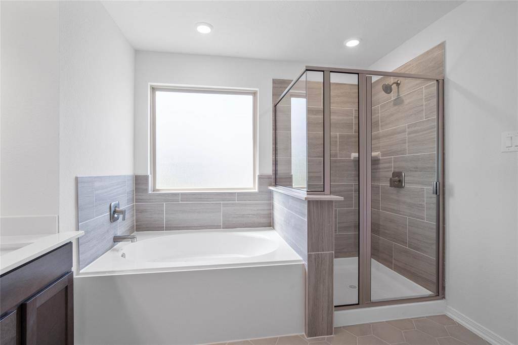 This view of the primary bathroom showcases the large garden tub and walk-in shower with tile surround!