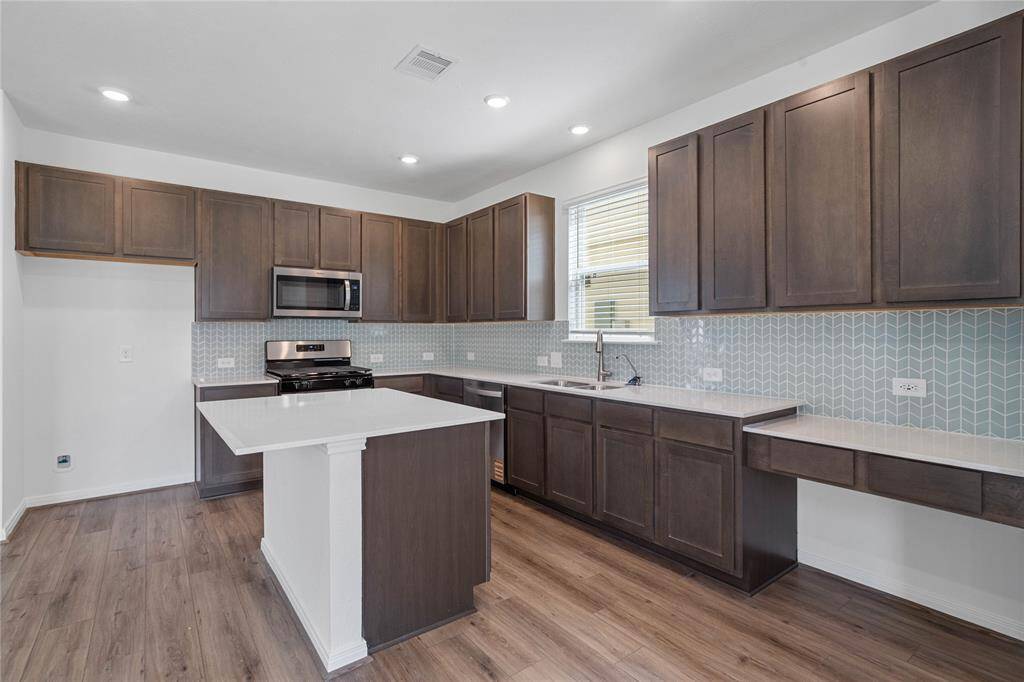 WOW! This kitchen will not disappoint! Your family and guests will enjoy many nights of fun, food and entertainment with ample counter space and kitchen island for setting up a wonderful array of provisions! This gorgeous kitchen showcases SS appliances including microwave, silestone countertops, added countertop on island for breakfast bar, modern tile backsplash, gas range, high ceiling, recessed lighting and vinyl plank floors!
