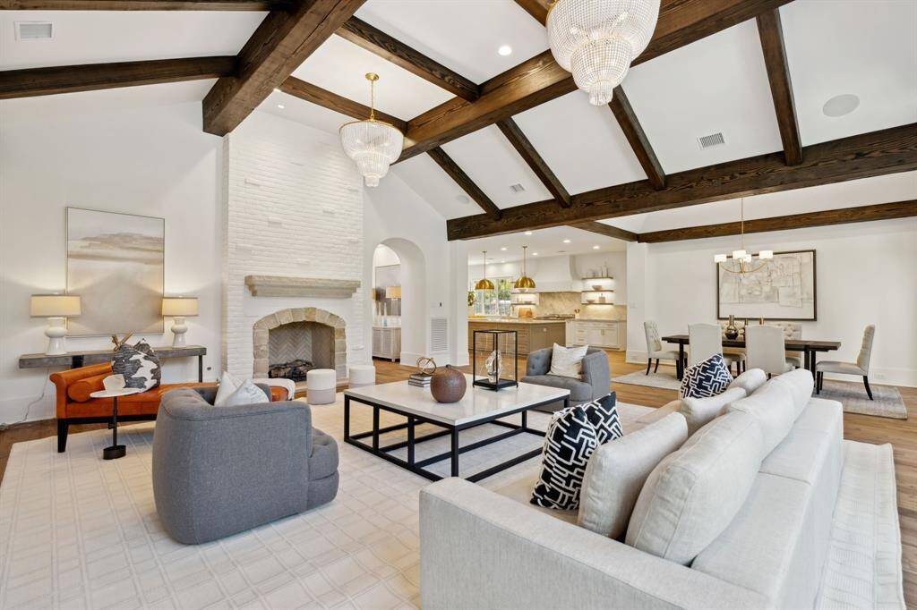 [Family Room] A spacious view of the open-concept living space with a cozy stone fireplace, designer chandeliers, and a seamless flow into the gourmet kitchen and breakfast area—perfect for entertaining.