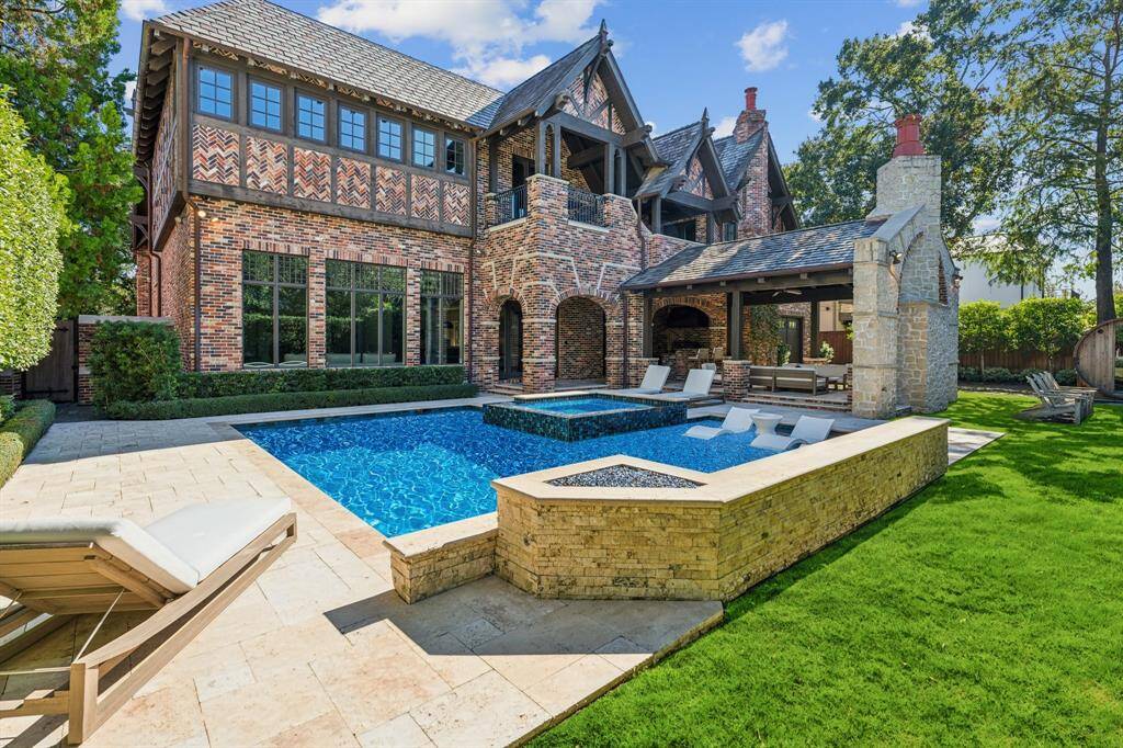[Exterior] Brick exteriors, copper gutters/downspouts, slate roof and travertine patios, The beautiful pool features a water feature and spa.