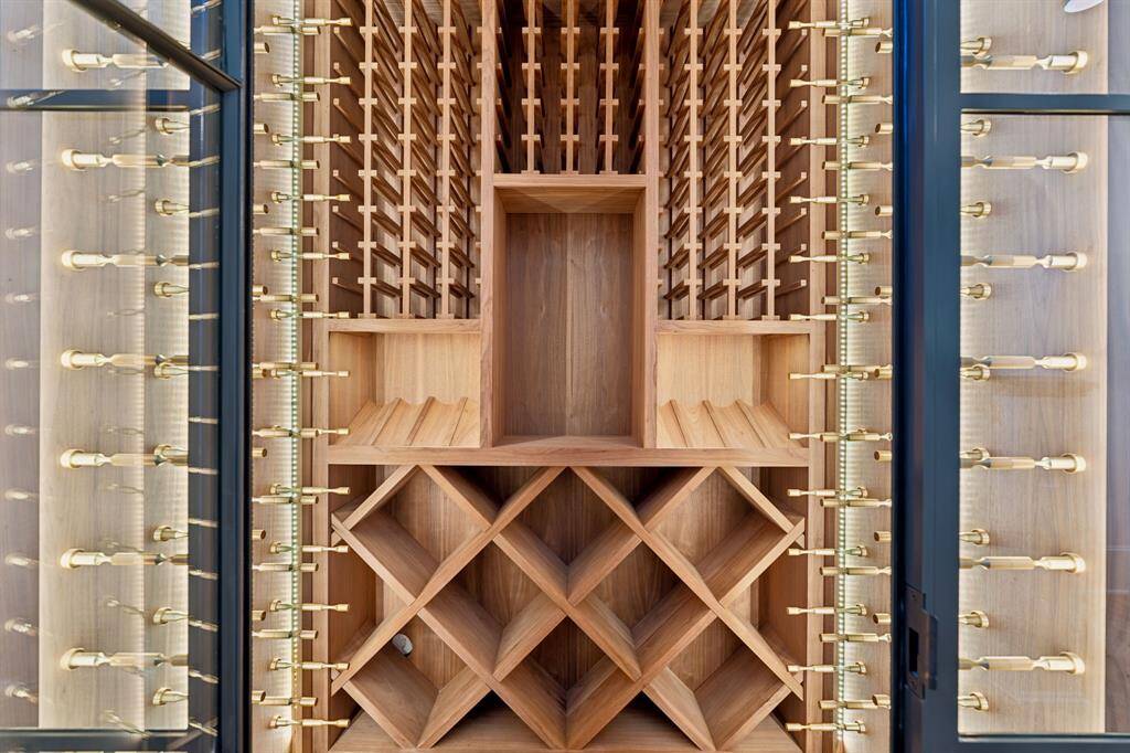 [Wine Room]. An elegant, custom-built wine room featuring natural wood shelving and brass hardware.