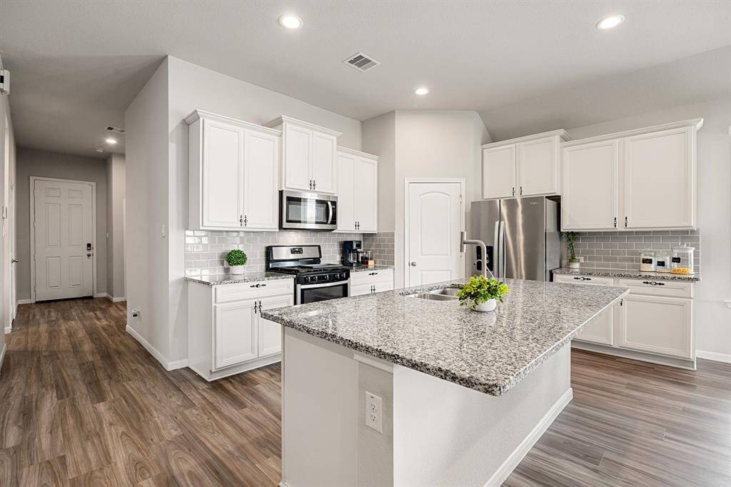 Expansive kitchen with granite countertops, a gas range, and stainless steel appliances. The large island includes seating for easy meals and entertaining!