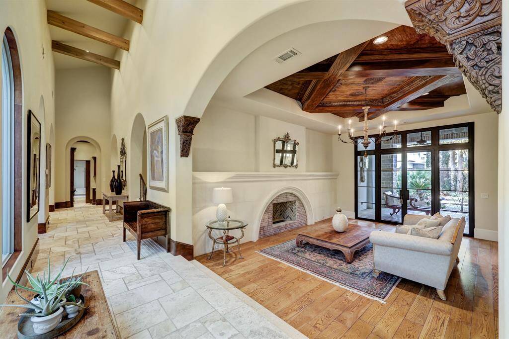 The formal sitting room exudes elegance with its elongated ambient fireplace mantel, intricately carved wood arch footings, and a stunning temple door seamlessly integrated into the timber ceiling design. Enhancing the sense of tranquility, an intimate covered patio with floor-to-ceiling French doors opens to a serene koi pond, creating a perfect indoor-outdoor retreat.