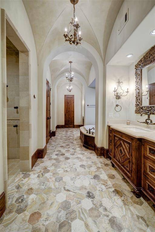 The primary bath offers a thoughtfully designed split layout, showcasing exquisite wood and stone accents throughout. This harmonious blend of natural materials creates a luxurious yet serene retreat.
