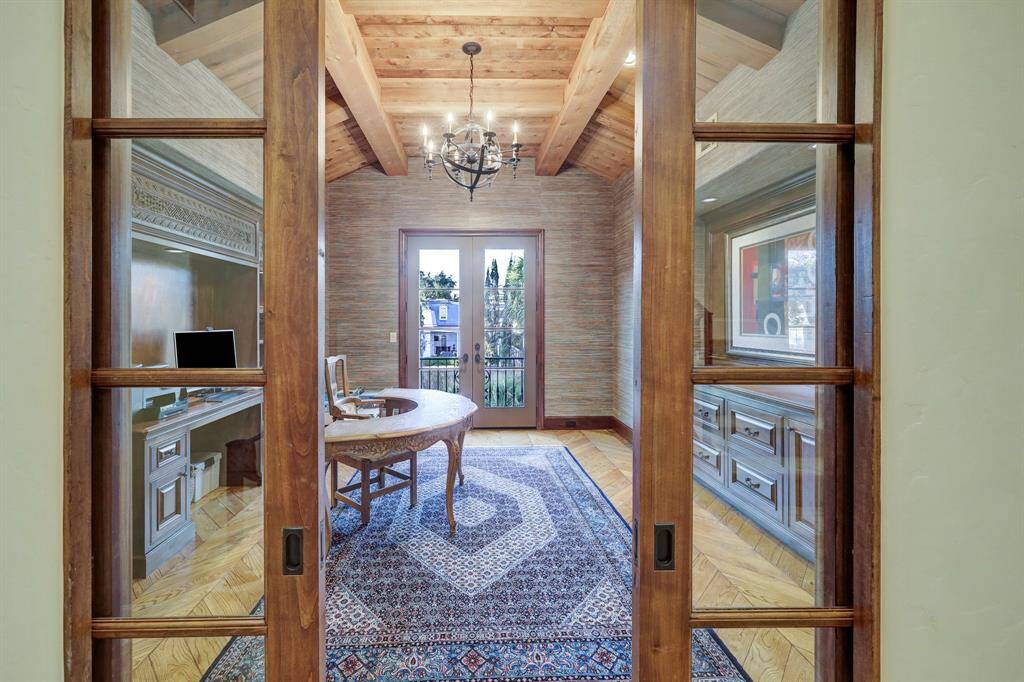 The study is a private retreat, set apart from the rest of the home for ultimate seclusion. With a distinct ambiance, it offers breathtaking views of the lush yard and shimmering pools, creating an inspiring and tranquil workspace.