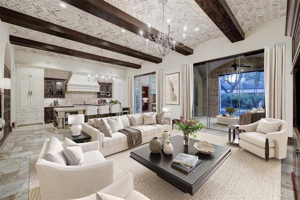 This breathtaking great room features an open design and expansive floor-to-ceiling French doors, seamlessly blending indoor and outdoor living. Adding both convenience and elegance, a hidden butler’s prep kitchen is cleverly concealed behind the right-side cabinet of the kitchen wall. *enhanced photo