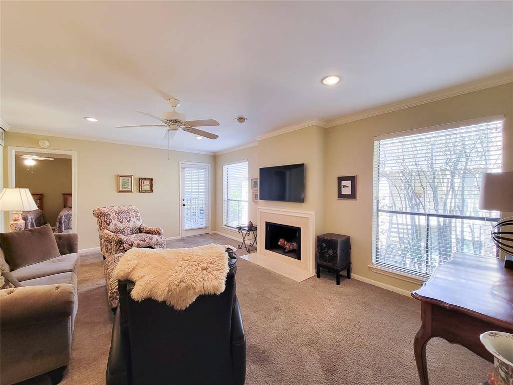Large windows flank the fireplace with marble surround and TV (that stays!) above it.