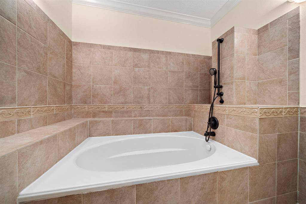 A deep soaking tub with tile surrounds offers a relaxing retreat, complemented by thoughtful design details and a built-in ledge for added convenience.