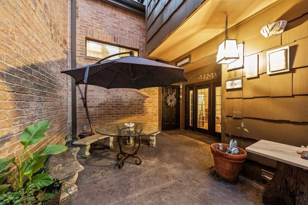 The front entry showcases a covered patio with ample space for a seating area or decorative accents, creating a versatile outdoor extension. Double glass doors framed by elegant lighting offer a warm transition into the home.