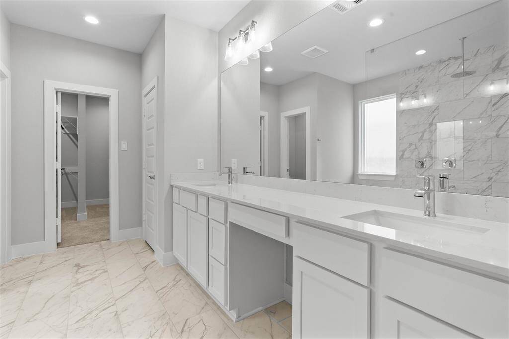 This primary bathroom is definitely move-in ready! Featuring stained wood cabinets with light countertops and dual vanities, spacious walk-in closet with shelving, high ceilings, custom paint, sleek and dark modern finishes.