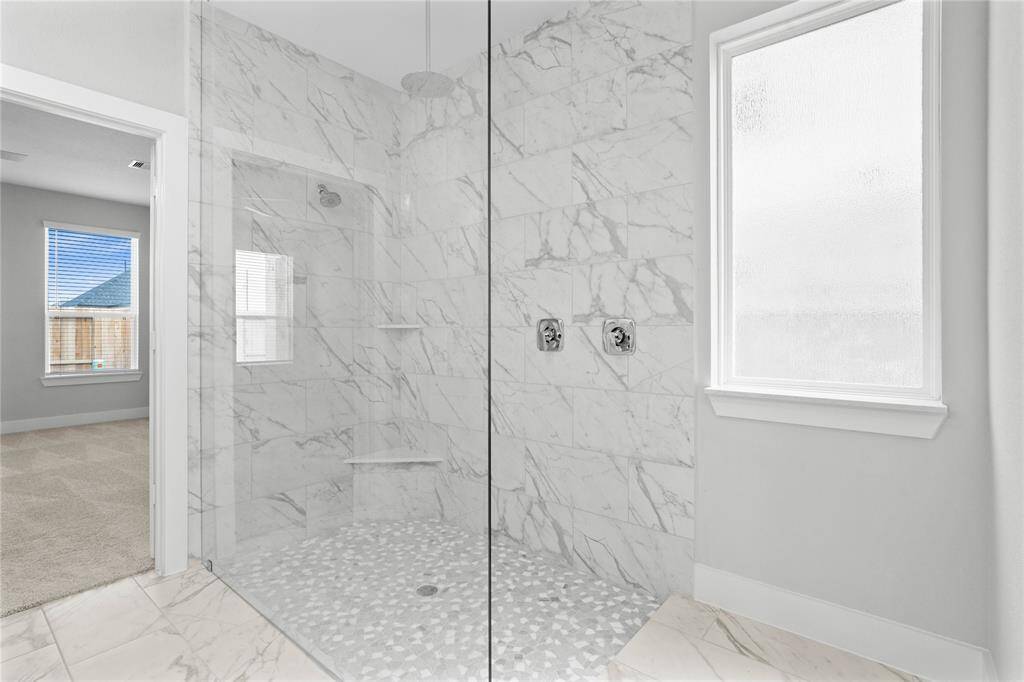 Additional view of this beautiful primary bathroom featuring the oversized walk-in shower with tile surround, high ceilings, custom paint, and a large window for natural lighting.