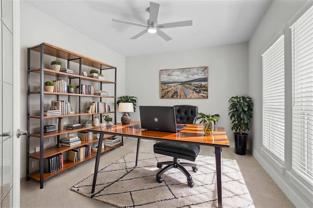 Quietly nestled in front of the home is the handsome home office! Featuring plush carpet, high ceilings, ceiling fan, large windows with privacy blinds, custom paint, and French doors!