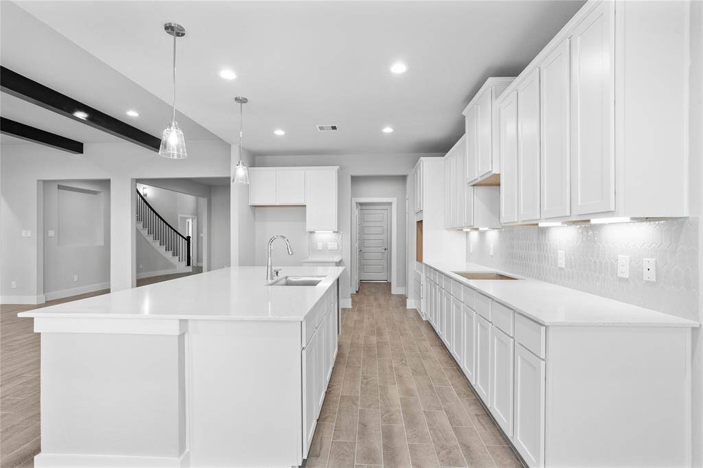 This kitchen is by far any chef’s dream! This spacious kitchen features high ceilings with recessed lighting, pendant lighting, stained wood cabinets, quartz countertops, modern tile backsplash, extended counter space, quartz kitchen island with space for breakfast bar, and a walk-in pantry all overlooking your huge family room.