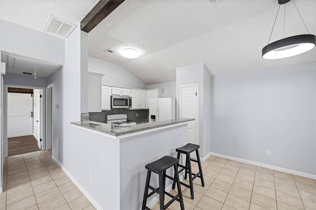 Wood beam accent, breakfast bar, granite tile counter tops, Shaker cabinet doors, upgraded doors.Hall leads to secondary bedrooms