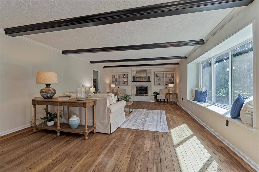 Spacious Family Room with wood beams, fireplace, wall of windows, wood flooring, and built-ins