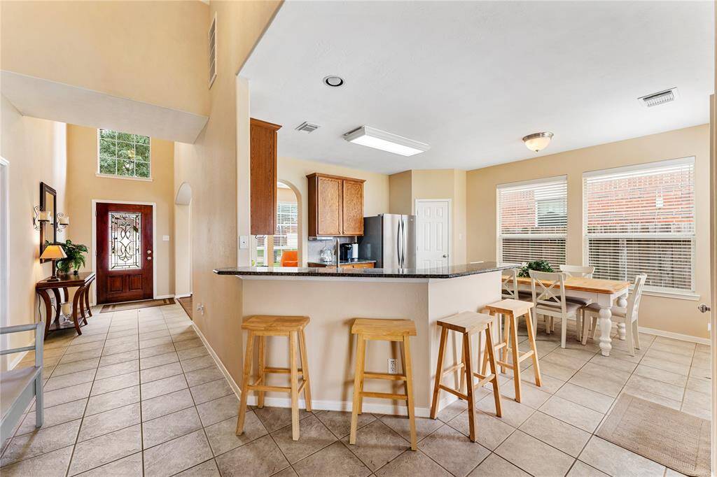 Bright and welcoming kitchen with stainless steel appliances, oak cabinetry, and a spacious breakfast area. Plus a convenient breakfast bar.