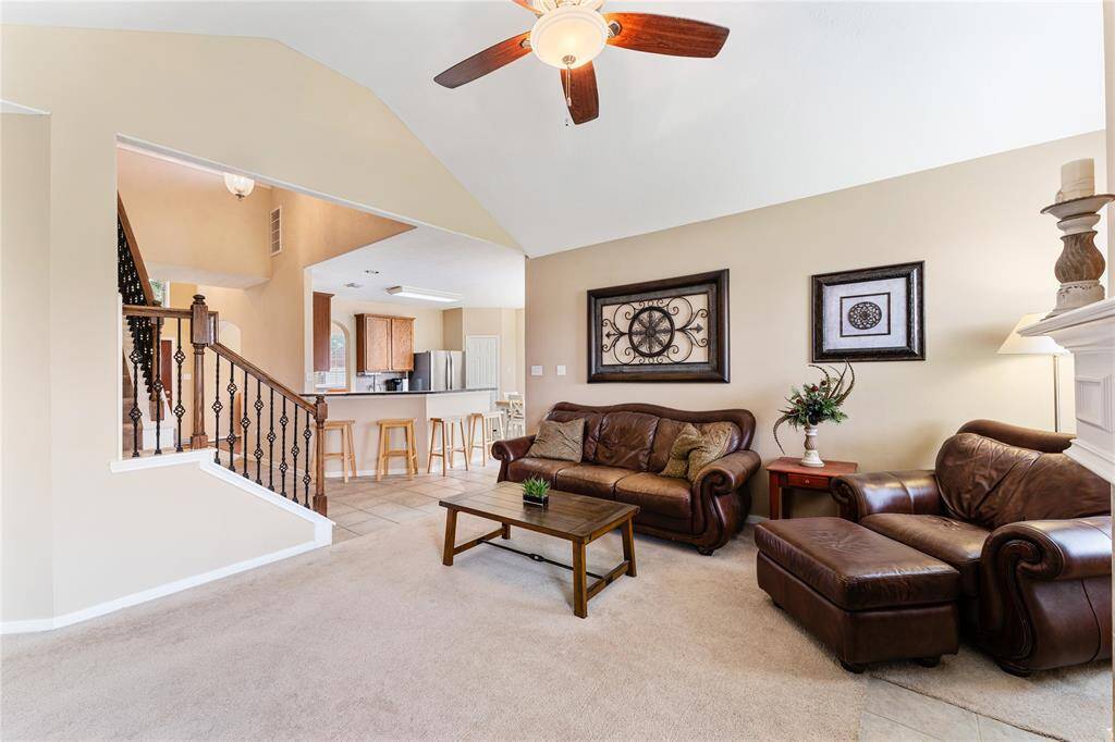 Bright and inviting living room with vaulted ceilings, featuring a cozy gas log fireplace and windows that overlook your private fully fenced backyard.