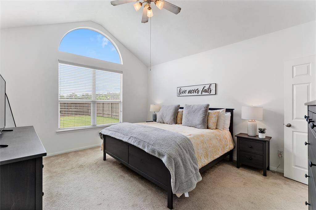 Inviting living room features a vaulted ceiling, and a warm neutral color palette. It includes a gas log fireplace, and ample natural light from two windows, creating a comfortable and stylish space.