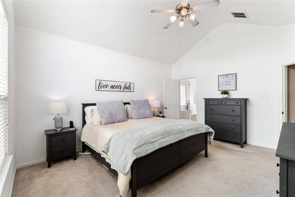 Primary bedroom with neutral paint, vaulting ceiling and ceiling fan.