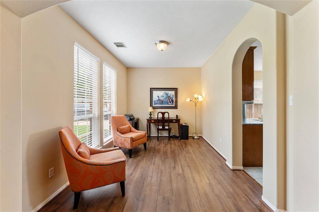 Welcoming entryway with a tiled floor, leading to an open-plan living area. Wooden front door with glass inlay door, the space is bright and airy, with warm neutral tones.