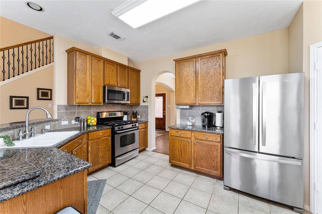 Bright and spacious kitchen with a breakfast nook, featuring large windows and overlooks the private backyard. You have stainless appliances, granite countertops and a dual basin sink. The open layout flows into the living area, highlighting a cozy fireplace. Perfect for family gatherings and entertaining.