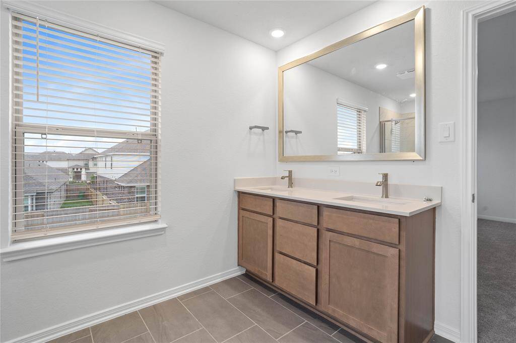This primary bathroom is definitely move-in ready! Featuring stained cabinets with light countertops, dual vanities, high ceilings, neutral paint, sleek and modern finishes.