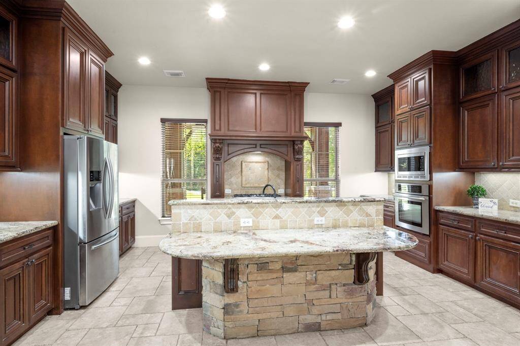 Massive double decker island allows the sink (and any messy dishes) to be hidden. Accent stone is carried into this space for a stunning visual.