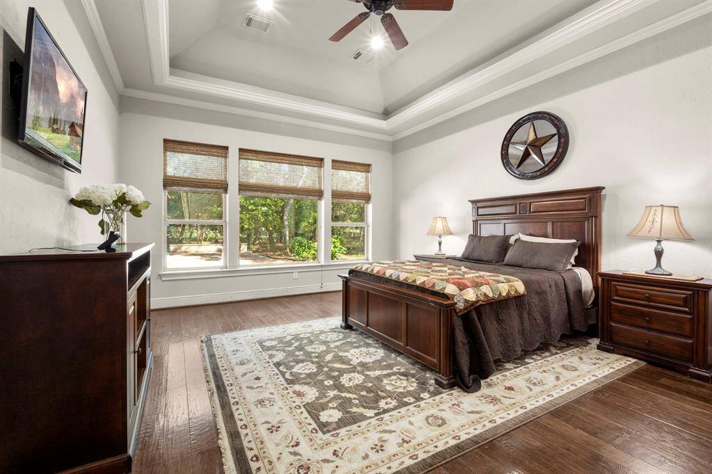 Primary suite offers uplighting from the crown moulding into the vaulted ceiling, large sun-filled windows, wood flooring, recess lighting and ceiling fan.