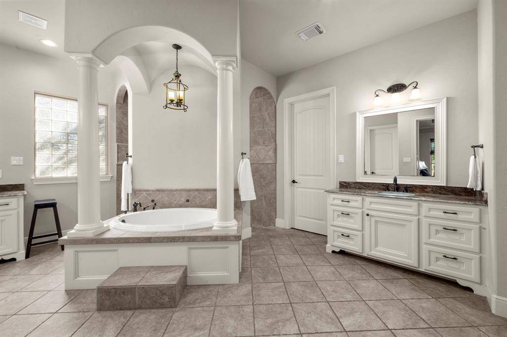 Neutral color palette, iron chandelier, jetted soaking tub, walk-in shower, framed mirrors and rubbed bronze fixtures.