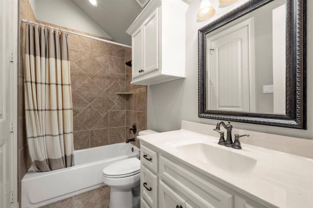Bath 3 - Upstairs bathroom with a tub/shower combo and decorative diamond patterned tile, framed mirror, elongated toilet, drawers and cabinets for storage.