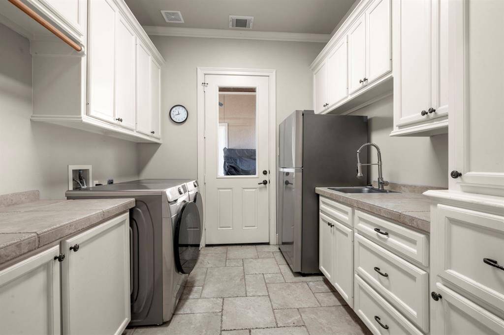 Laundry room offers access to the back patio. A laundry shoot from the upstairs empties to the right cabinet. A laundry sink, counter space, hanging rod and fridge space offers all that you need in a laundry room and more. *W/D/F are excluded.
