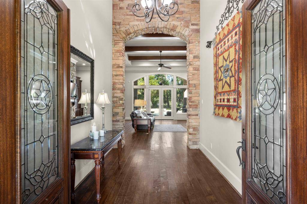 Immediate views of the stoned archway, wood beams and wide foyer with sunlight streaming into the home.