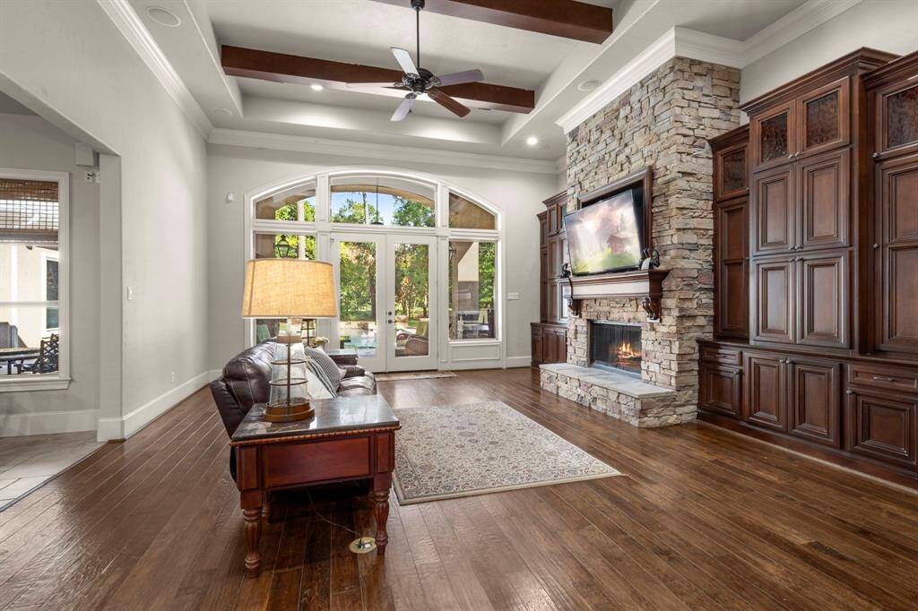 The stone is carried onto the massive fireplace wall which is flanked by custom cabinetry. The top-tier provides glass doors and lighting for your favorite display pieces. Appreciate all of the natural light and the views to the back yard.