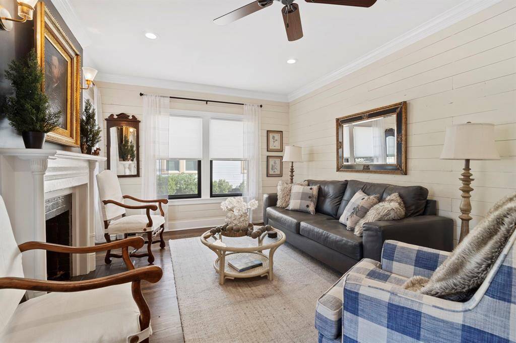 Delightful living room is surrounded by windows and features recessed lighting, insulated shiplap walls, hardwood floors, crown molding, ceiling fan, and gas-log or wood burning fireplace.