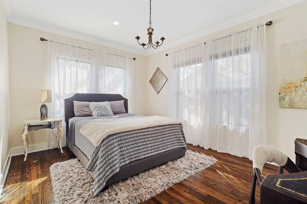 Pretty guest bedroom features a vintage chandelier, windows on two walls, and a walk-in closet.