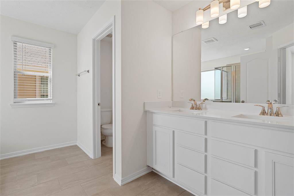 This large primary bath is spacious enough to share! With separate vanities, plentiful cabinet and counter space, you are sure to have private area while sharing this bathroom!