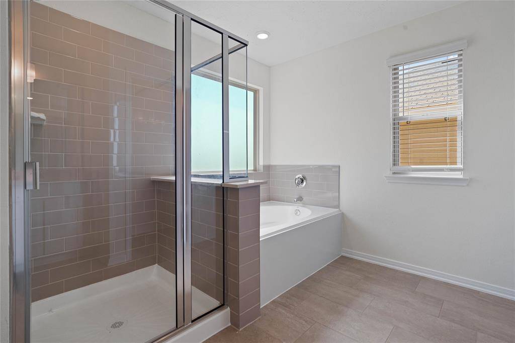 This primary bathroom is definitely move-in ready! Featuring a walk-in shower with tile surround, separate garden tub for soaking after a long day with custom tile detailing, custom paint, sleek and large windows to bring in the natural light.