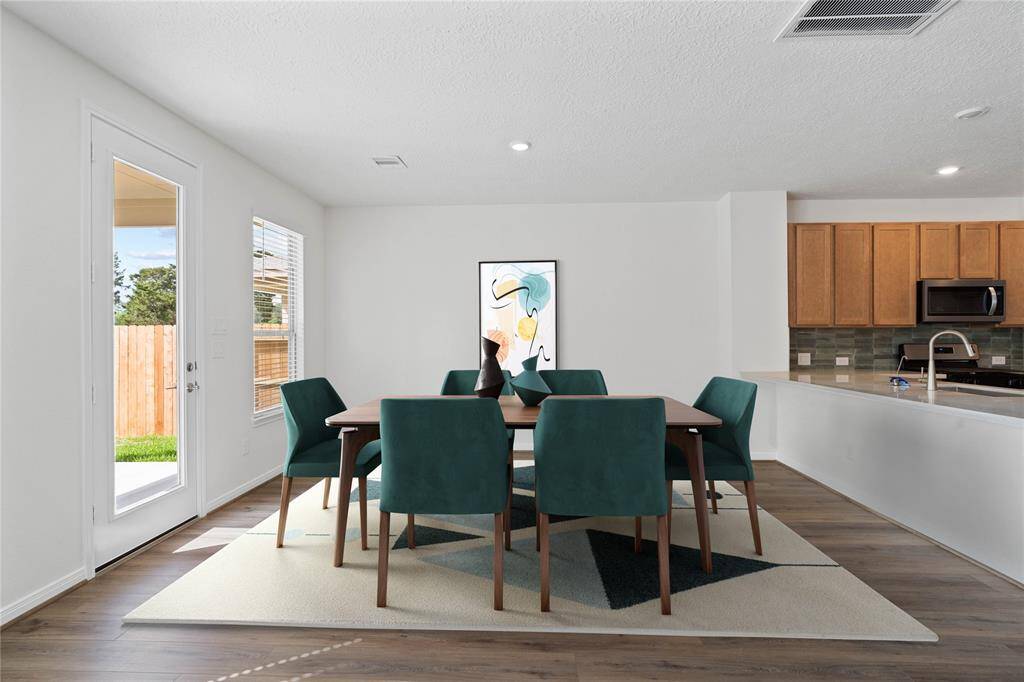 The open concept family, dining and kitchen makes for a great way to keep the party going and never miss a beat! The dining room here features vinyl plank flooring, large window with blinds, warm custom paint, and access to the back yard.