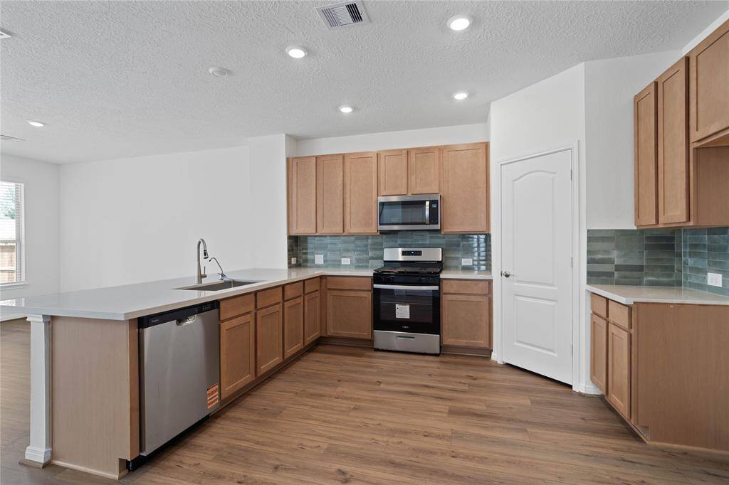 Another view of this spacious kitchen showcasing the gorgeous modern tile backsplash, SS appliances, and silestone countertops.