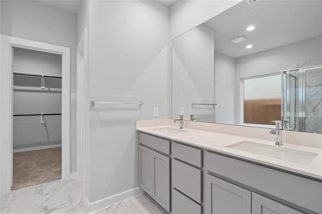This primary bathroom is definitely move-in ready! Featuring stained cabinets with light countertops, dual vanities, spacious walk-in closet with shelving, high ceilings, custom paint, sleek modern finishes.