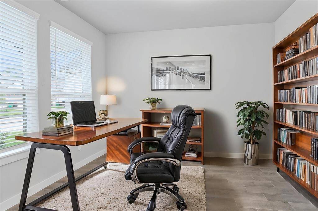 Quietly nestled in front of the home is the handsome home office. Featuring wood look tile flooring, high ceilings with ceiling fan, large windows with privacy blinds and custom paint.