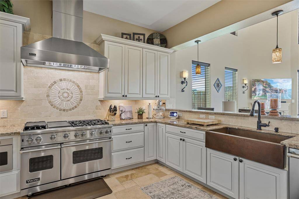 Featuring double Viking ovens and a sleek stainless steel hood, this kitchen makes cooking effortless.