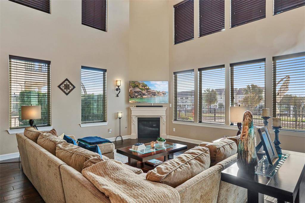 This living room features soaring ceilings and abundant natural light, creating a cozy haven by the fireplace.