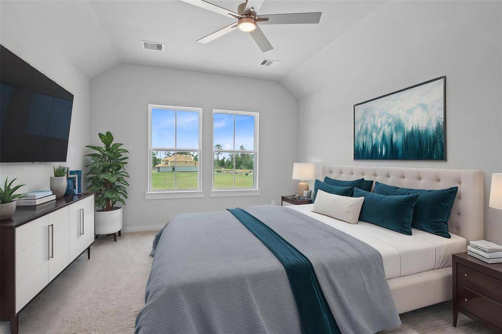 Secondary bedroom features plush carpet, custom paint, ceiling fan with lighting, closet space, and large windows!