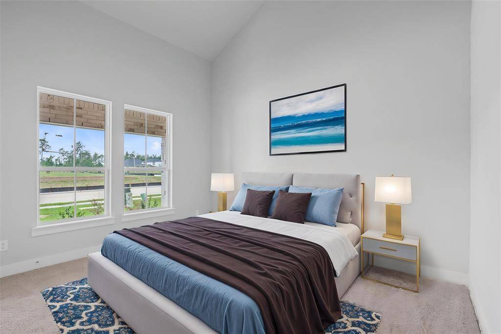 Quietly nestled in front of the home is a secondary bedroom. Featuring high ceilings, custom paint, plush carpet flooring, and large windows.