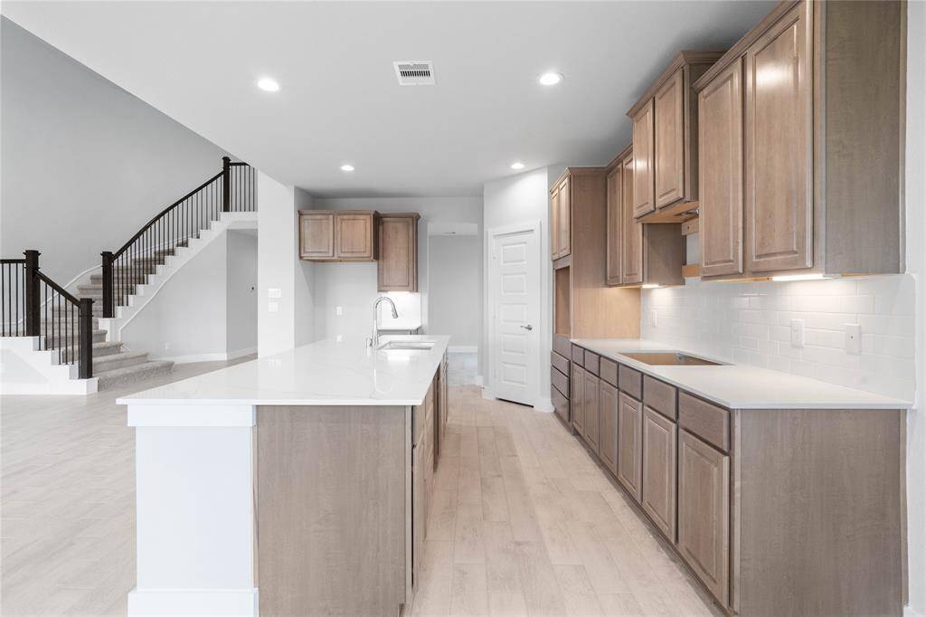 This kitchen is by far any chef’s dream! This spacious kitchen features high ceilings, stained wood cabinets, quartz countertops, modern tile backsplash, recessed and under cabinet lighting, quartz kitchen island with space for breakfast bar, extended counter space, and a walk-in pantry all overlooking your huge family room.
