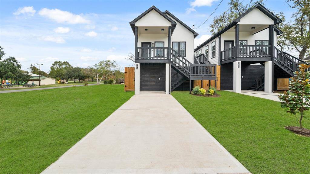 Modern home with elevated design features, including black and white exterior, front porches, and ample green space. Located near a park, offering a serene neighborhood setting.