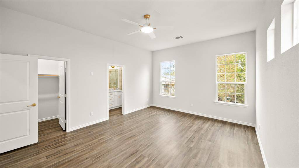 Spacious primary suite featuring elegant flooring, abundant natural light, and a private en-suite bath for ultimate comfort and style.
