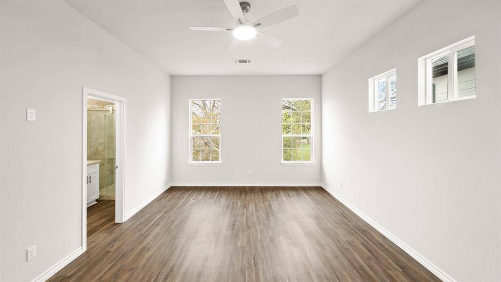 Spacious primary suite featuring abundant natural light, elegant flooring, and an en-suite bathroom for ultimate comfort and privacy.